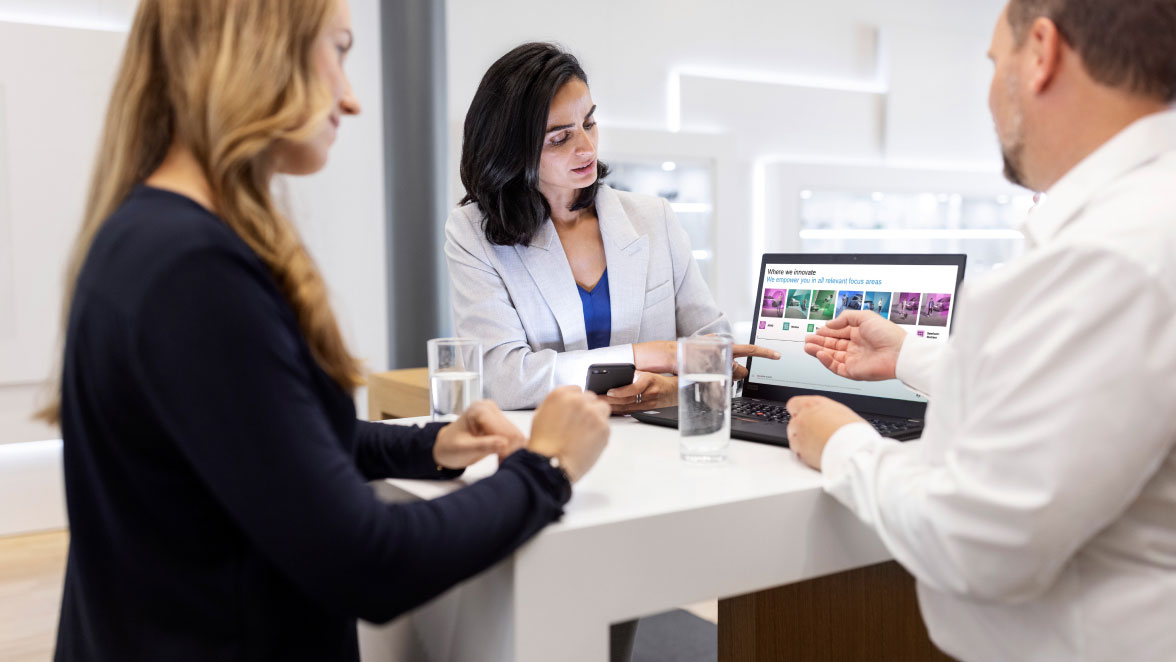 Drei Menschen in moderner Bürosituation besprechen sich an einem Laptop