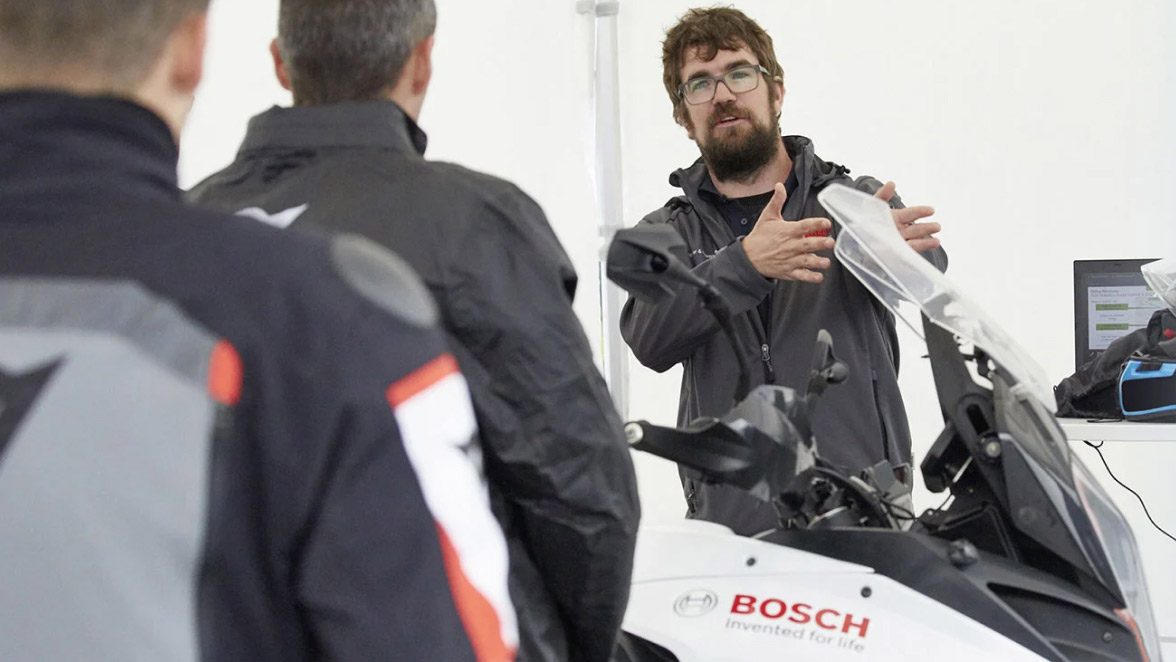 A team stands around a vehicle and discusses the installed technology